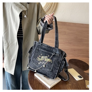 Detail of vintage black denim tote bag with colorful embroidery and pearl chain strap