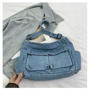 Detail of light blue denim tote with large front flap pockets and adjustable strap