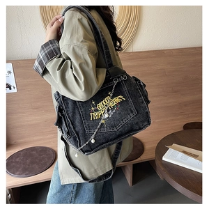 Vintage black denim tote bag with yellow embroidery and pearl chain detail worn by model