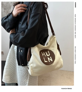 Detail of off-white canvas tote with brown HULN leather patch and shoulder strap style