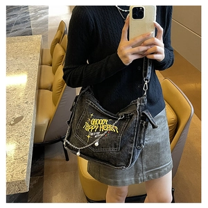 Detail of grey denim bag featuring yellow embroidery text and a metal chain with pearls