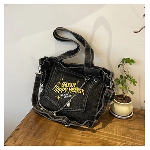 Detailed view of embroidery and pearl chain on washed denim black tote bag