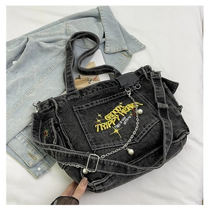 Detail of black denim tote with yellow embroidery and pearl chain accessory decoration