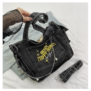 Detail of black denim tote bag with yellow embroidery and pearl metal chain strap