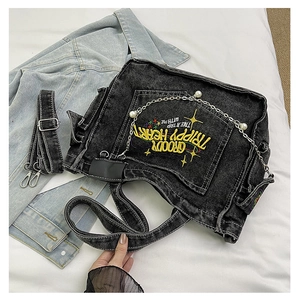 Detail of black denim tote bag with vibrant yellow embroidery and pearl metal chain