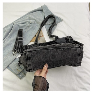 Detail of vintage washed grey denim tote bag showing adjustable strap and side pocket