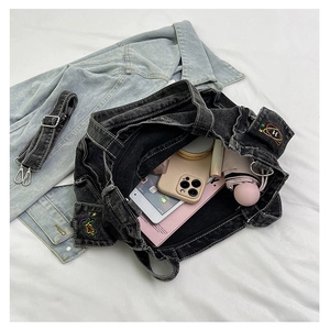 Flat lay of washed denim tote bag showing spacious interior with embroidery patches