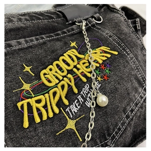 Detail of 3D puff embroidery and pearl chain on washed denim shoulder bag