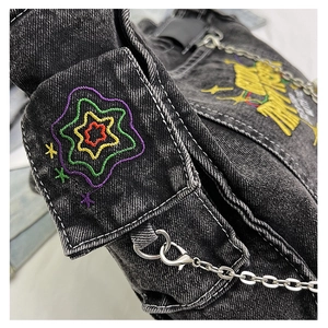 Detail of colorful star embroidery and silver metal chain on washed denim shoulder bag