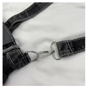 Detail of silver metal swivel hook and white stitching on gray washed denim shoulder strap