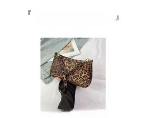 Dettaglio borsa sottobraccio leopardata con catena dorata su giacca in denim