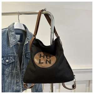 Large black canvas tote bag with adjustable brown leather straps for shoulder or backpack use