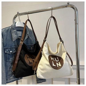 Large casual canvas tote bags in black and cream with brown leather straps and logo patch