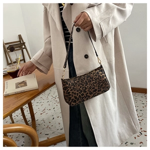 Dettaglio della borsa baguette leopardata con tracolla in pelle nera e fibbie dorate