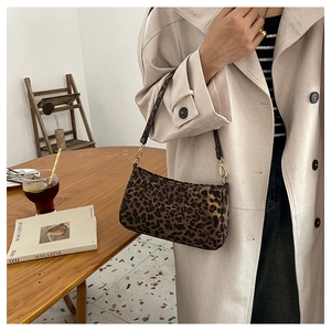 Dettaglio della borsa baguette leopardata con fibbie dorate e morbida texture in camoscio