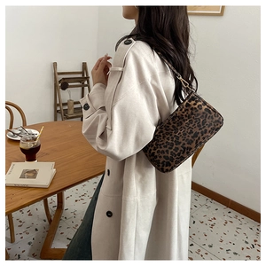 Dettaglio borsa a spalla leopardata con fibbie dorate indossata su un trench beige
