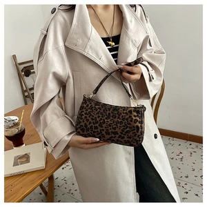 Dettaglio della borsa a spalla leopardata abbinata a un trench beige in un caffè