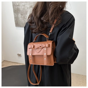 Detailed back view of model wearing a caramel brown PU leather crossbody bag with bow