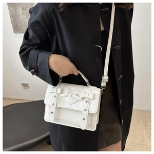 White JK style messenger bag with heart pattern and bow detail shown on a model