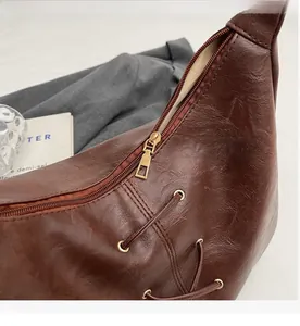 Detail view of smooth metal zipper and vintage brown leather texture on a tote bag