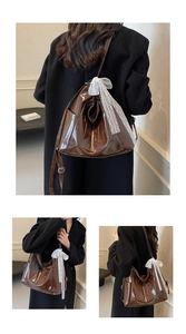 Detail of dark brown faux oil leather tote bag with white lace bow and side pocket