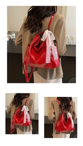 Detail of red faux leather backpack with large white lace bow and smooth metal zipper