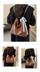 Detailed macro view of brown glossy leather bag featuring M embossed design and lace bow
