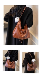 Detail of brown PU leather tote bag with unique shoelace lacing and plush pendant accessory