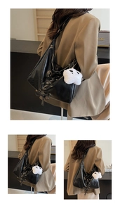 Detail of black large tote bag featuring side lace-up bows and a star plush charm