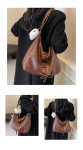 Detail of brown vintage tote bag with lace-up ribbon and white ghost plush charm