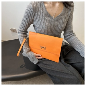 Detail der orangen Umschlag-Clutch mit Metallschleife und Handschlaufe am Modell