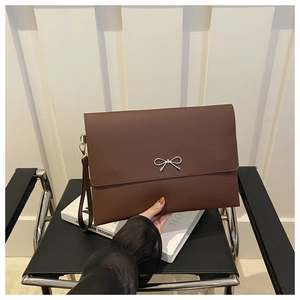 Detail der braunen Umschlag-Clutch mit silberner Metallschleife und abnehmbarer Handschlaufe
