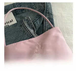 Close-up of pink nylon shoulder bag with elegant 'pretty and libety' embroidery detail
