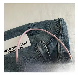 Close-up of slim rounded handle on light pink nylon shoulder bag with matte finish