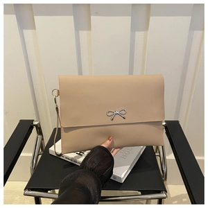 Detail einer beigen Umschlag-Clutch mit silberner Metallschleife und Handschlaufe