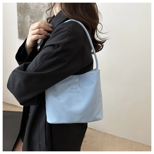 Detail of light blue nylon bag featuring navy blue pretty and libety embroidery