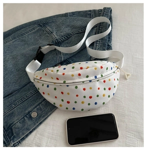 Close-up of white polka dot chest bag on denim jacket with a smartphone as size guide