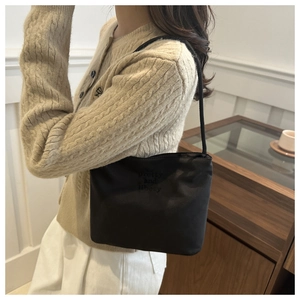 Fashionable black nylon shoulder bag with embroidery on a beige sweater model