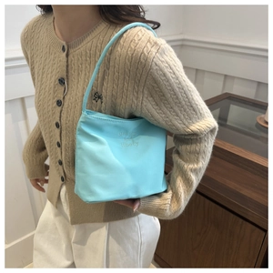 Detail of light blue nylon handbag featuring embroidery and cozy knit styling