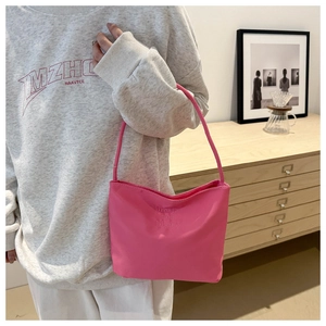 Detail of pink nylon bucket bag featuring embossed text and slim shoulder strap