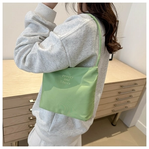 Detail of green nylon shoulder bag with pretty and libety text shown on model side view