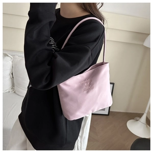 Detail of light pink nylon shoulder bag featuring elegant cursive letter embroidery