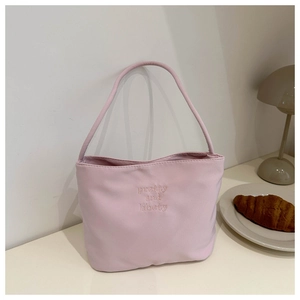 Detail of pink canvas tote bag with yellow embroidery on an elegant cafe table