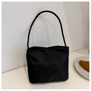 Close-up of black nylon shoulder bag featuring white pretty and libety embroidery