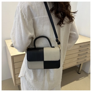 Dettaglio di una borsa a mano patchwork bianca e nera indossata come borsa a tracolla