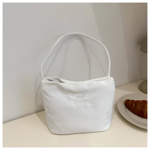Detail showing white bucket bag with 'pretty and libety' embroidery in a cafe setting
