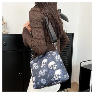 Gothic skull and flower jacquard bucket bag shown with a wide nylon shoulder strap