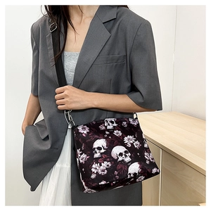 Detailed view of skull and floral jacquard shoulder bag worn by model with suit