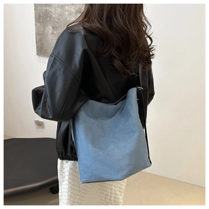 Minimalistische Schultertasche aus dunkelblauem Denim, am Modell im Vintage-Stil