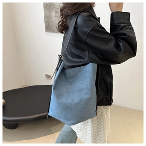 Detail der blauen Denim Beuteltasche mit schwarzem Lederriemen und Metallschnalle